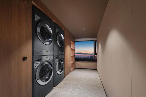 a laundry room with three washing machines and a window at Atour Hotel Xi'an South Yanta Road Jinhui Plaza in Xi'an