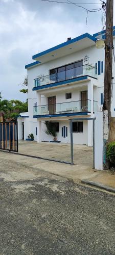a white building with a blue roof on a street at Vista al mar live in La Puntica de Juan Dolio