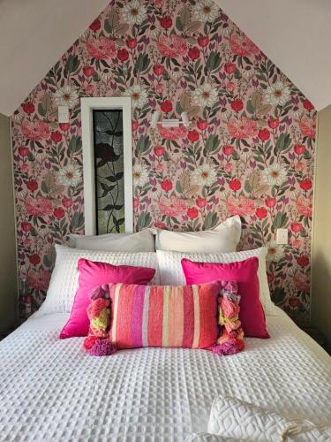 a bedroom with a large bed with pink pillows at Forest Waters Raspberry Dream Cabin in Haruru