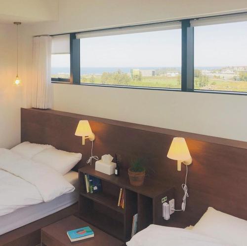 a bedroom with two beds and two windows at Deokin Mansion in Jeju