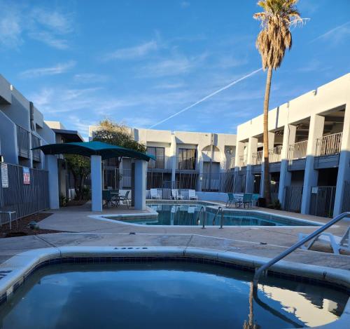 a pool with a palm tree in front of a building at Las Palmas Airport Inn in Tucson