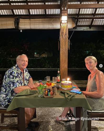 two older people sitting at a table with a birthday cake at Cocotinos Lembeh a Boutique Dive Lodge in Bitung