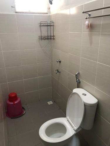 a bathroom with a toilet and a red trash can at Zahara Homestay in Sandakan