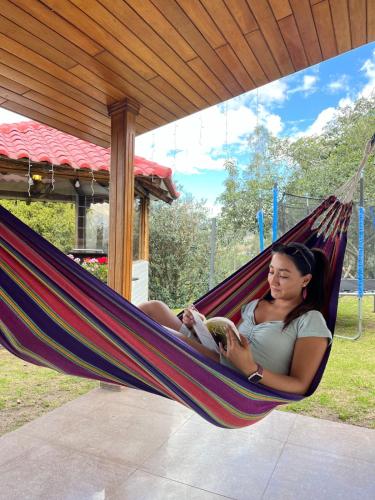 a woman laying in a hammock reading a book at Casa rústica con vista increíble y aire fresco in Quito
