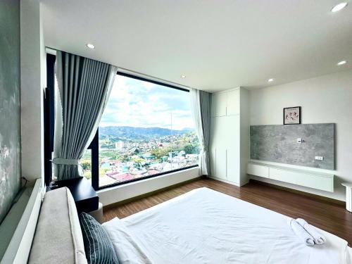 a bedroom with a large window with a large bed and a large bed sidx sidx at Gấu House Villa in Da Lat