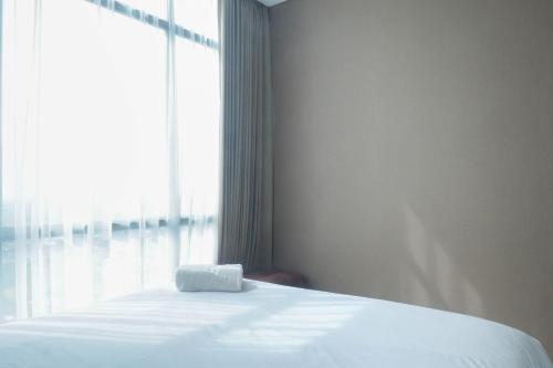 a bed in a room with a large window at Vibrant Luxurious 2BR Apartment at Aryaduta Residence Connected to Cito Mall By Travelio in Surabaya