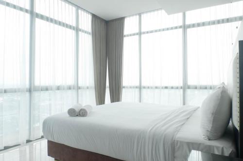 a bedroom with a large bed with two towels on it at Vibrant Luxurious 2BR Apartment at Aryaduta Residence Connected to Cito Mall By Travelio in Surabaya
