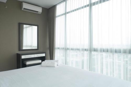 a bedroom with a white bed and a large window at Vibrant Luxurious 2BR Apartment at Aryaduta Residence Connected to Cito Mall By Travelio in Surabaya