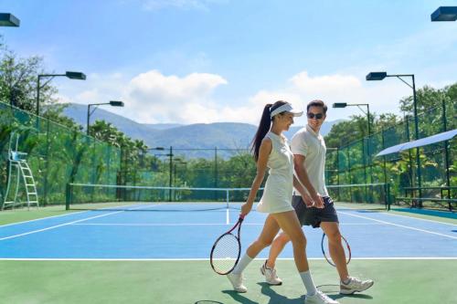 a man and a woman walking on a tennis court at Nha Trang Marriott Resort & Spa, Hon Tre Island in Nha Trang