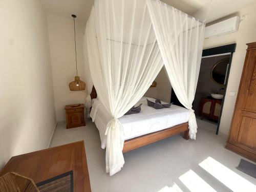 a bedroom with a canopy bed with white curtains at Villa KAS Legian Seminyak - 6 Bedroom Villa in Seminyak