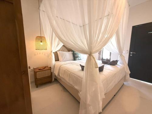 a bedroom with a white canopy bed with a window at Villa KAS Legian Seminyak - 6 Bedroom Villa in Seminyak