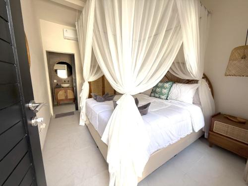 a bedroom with a white bed with a canopy at Villa KAS Legian Seminyak - 6 Bedroom Villa in Seminyak