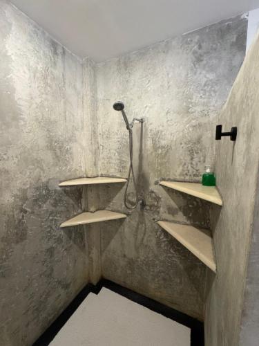 La salle de bains est pourvue d'une douche et d'étagères murales. dans l'établissement Uluwatu Stay's Standard Room #3, à Uluwatu