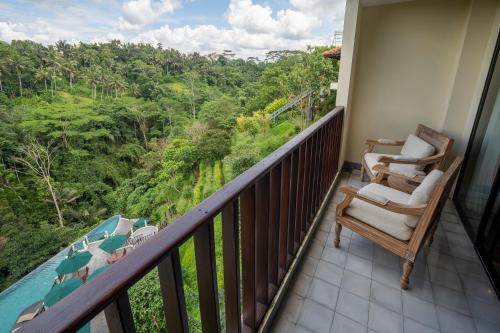 a balcony with two chairs and a view of the forest at Metland Venya Ubud in Ubud