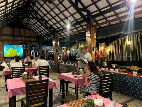 a man preparing food in a restaurant with people sitting at tables at Cocotinos Lembeh a Boutique Dive Lodge in Bitung