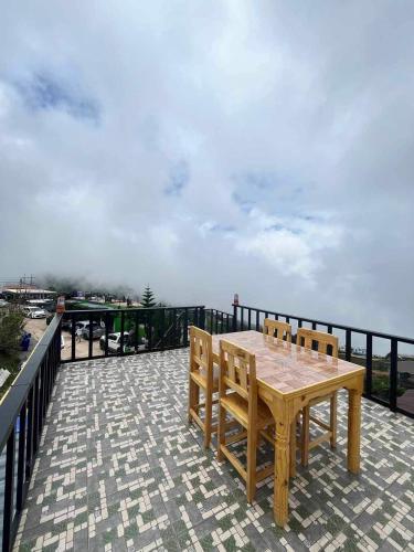a wooden table and chairs on top of a balcony at วิมานหมอก ภูทับเบิก in Ban Maeo Thap Boek