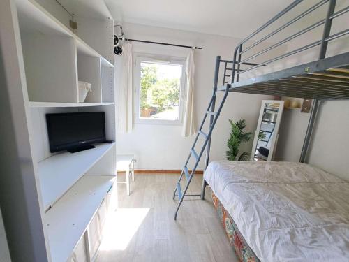 - une chambre avec des lits superposés et une télévision dans l'établissement Maison mitoyenne climatisée 7 pers. avec piscine et parking à Marseillan-Plage - FR-1-326-848, à Marseillan