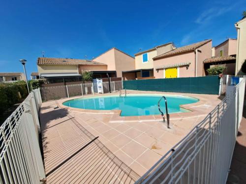 une piscine en face d'une maison avec une clôture dans l'établissement Maison mitoyenne climatisée 7 pers. avec piscine et parking à Marseillan-Plage - FR-1-326-848, à Marseillan
