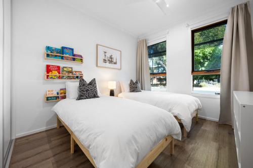 Dos camas en una habitación blanca con ventana. en Chalfont Way @ Glengowrie - WiFi BBQ Family, en Somerton Park