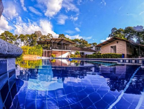 a swimming pool in front of a house at Hotel Campestre Nogal de Cafetal in Quimbaya