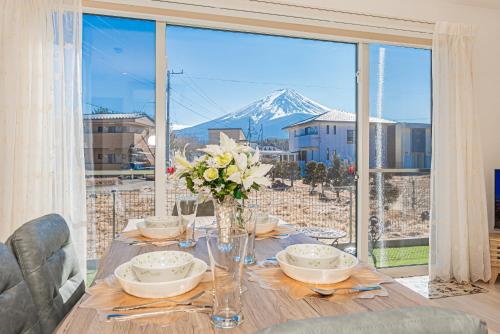 a dining room table with a view of a mountain at New Open! Collab House 富士山眺望 送迎無料 BBQ 器具無料貸出 in Fujikawaguchiko