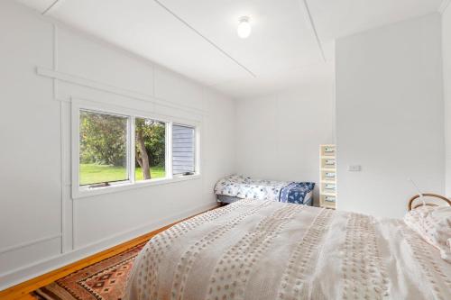 een witte slaapkamer met een bed en een raam bij Springs Beach House in Point Lonsdale