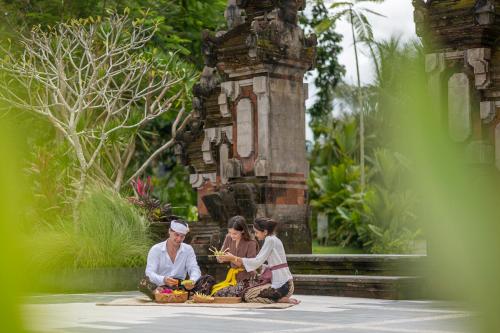 three women sitting on the ground in front of a fountain at Metland Venya Ubud in Ubud