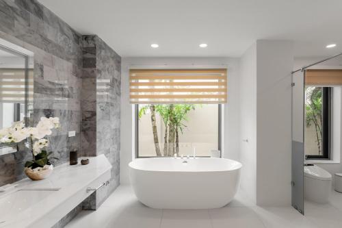 a white bathroom with a tub and a window at 拉古娜高尔夫俱乐部别墅 in Ban Nong Chaeng