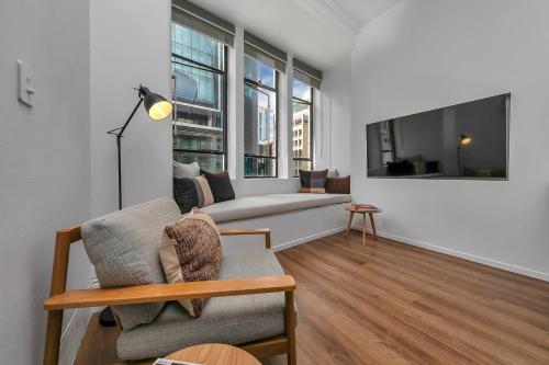 a living room with a couch and some windows at Historic Modern Luxury 1-Bedroom on Queen Street in Auckland