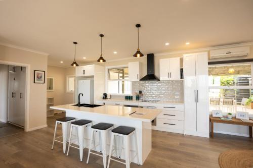 a kitchen with white cabinets and a island with bar stools at Captains on the Seafront - Breathtaking Sea views- Large 4br 2bth in Kingscote