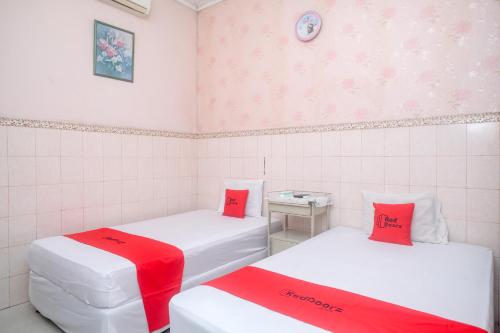 two beds in a small room with red pillows at RedDoorz Syariah at Griya Raharja Klaten in Klaten