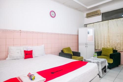 a small room with a bed and two chairs at RedDoorz Syariah at Griya Raharja Klaten in Klaten