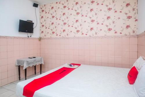 a room with a bed with a red blanket on it at RedDoorz Syariah at Griya Raharja Klaten in Klaten