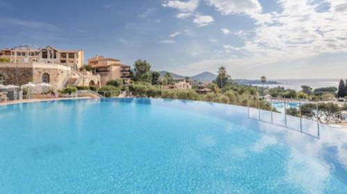 un grand bassin d'eau bleue avec des bâtiments en arrière-plan dans l'établissement Appartement LES PETITS PRINCES, à Agay