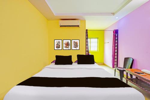 a bedroom with a large bed with yellow walls at Hotel O Ranipet Vellore formerly Ars Residency in Pallikondai