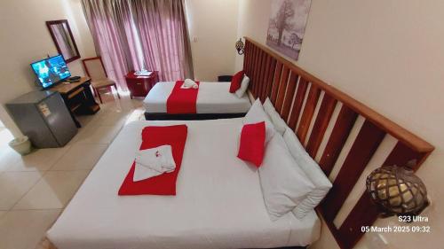 a bedroom with two beds with red and white pillows at Comfort Palace Guest House Kasane in Kasane