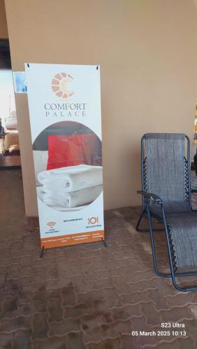 a sign for a bed in a room with a chair at Comfort Palace Guest House Kasane in Kasane
