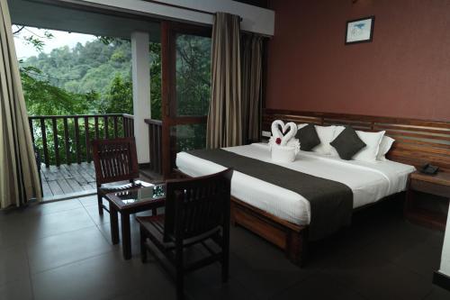 a hotel room with a bed and a balcony at Wayanad Silverwoods Forest Resort & Spa in Padinjarathara