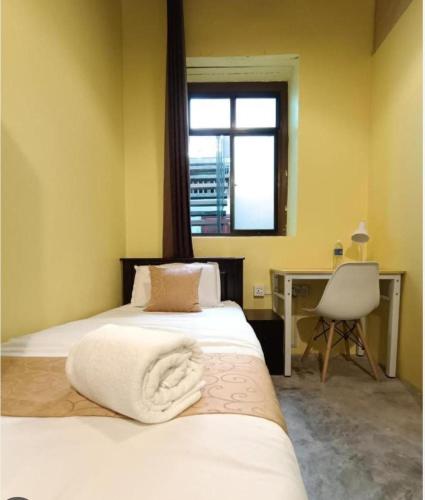 a bedroom with two beds and a desk and a window at Hotel Lang Hoose in George Town