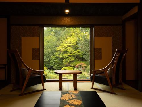 a room with a table and two chairs and a window at Ryumontei Chiba Ryokan in Ōyu