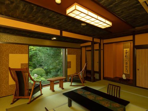 a room with a table and chairs and a window at Ryumontei Chiba Ryokan in Ōyu