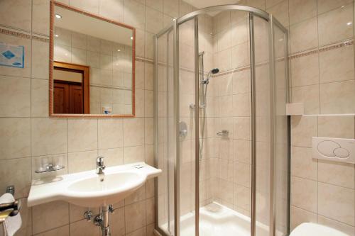 a bathroom with a shower and a sink and a mirror at Gasthof Aschenwald in Westendorf