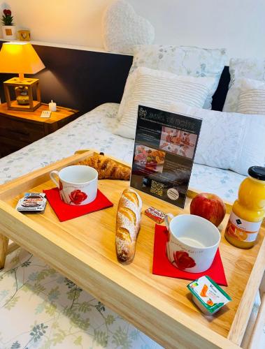 - un plateau de nourriture sur un lit avec 2 tasses et du pain dans l'établissement BELLEVUE -Appartement de Charme - Vue imprenable sur la Mer - Face à Nausicàa, à Boulogne-sur-Mer