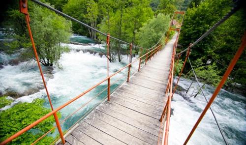 a suspension bridge over a river with white water at Auto Kamp Lav in Kulen Vakuf