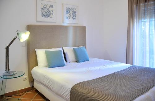 a bedroom with a large bed with blue pillows at Praia Del Rey ByThe Pools in Casal da Lagoa Seca
