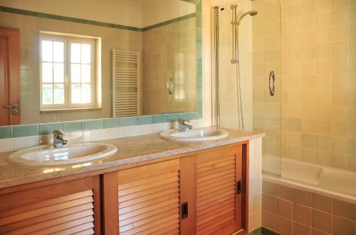 a bathroom with two sinks and a shower and a tub at Praia Del Rey ByThe Pools in Casal da Lagoa Seca