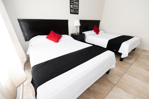 two beds with red pillows in a room at Boca Inn Hotel & Suites in Veracruz