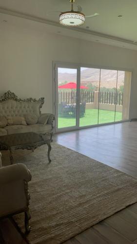 a living room with a couch and a large sliding glass door at Wadi Bani Khalid Villa in Dawwah