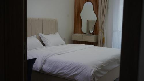 a bedroom with a white bed and a mirror at Wadi Bani Khalid Villa in Dawwah