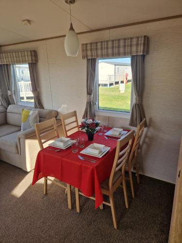 a dining room with a table and chairs and a couch at The Pearl - Deluxe Access Caravan in Skegness